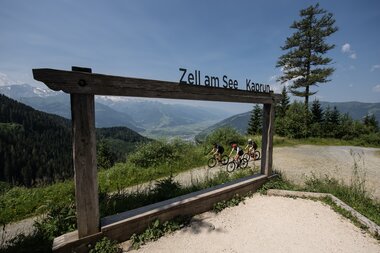 View of the mountains at Zell am See-Kaprun, visible through an open wooden frame with bicycle sculptures in front. | © Österreich Werbung / Miloš Štáfek